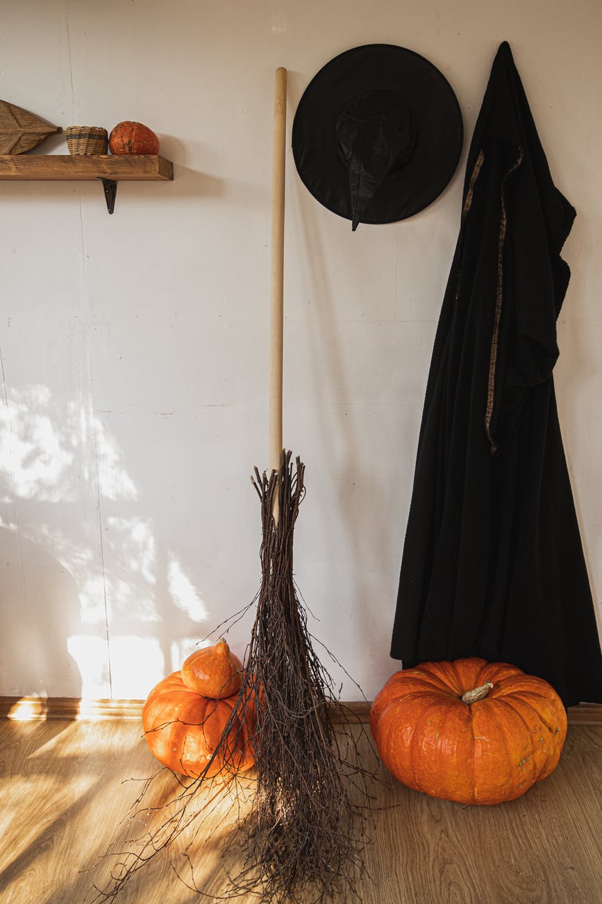 orange pumpkin beside black witch costume and a broom