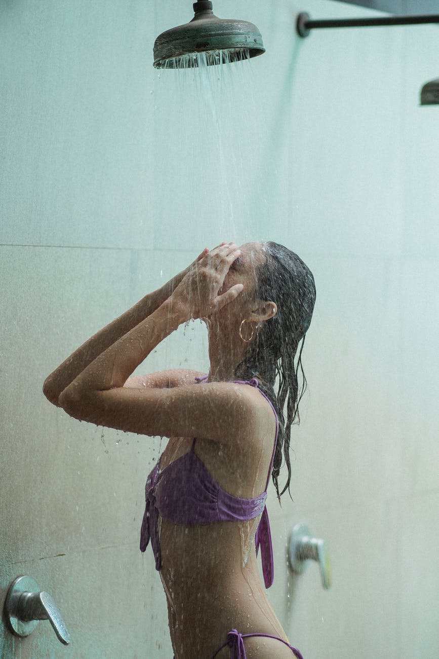 sensual woman in bikini under stream in shower