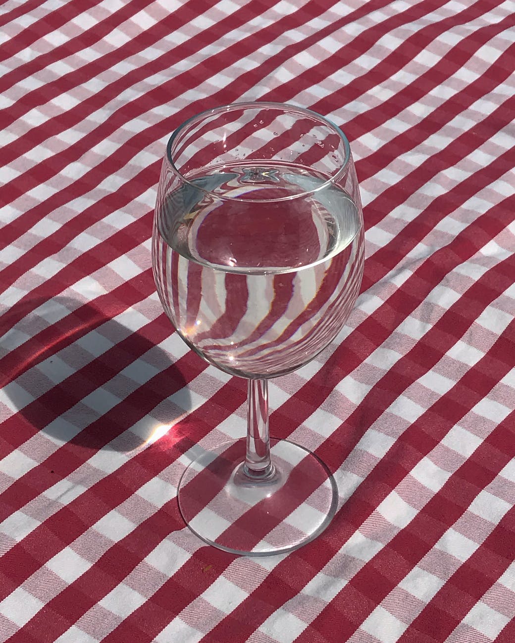 wine glass with water on a red checkered table cloth